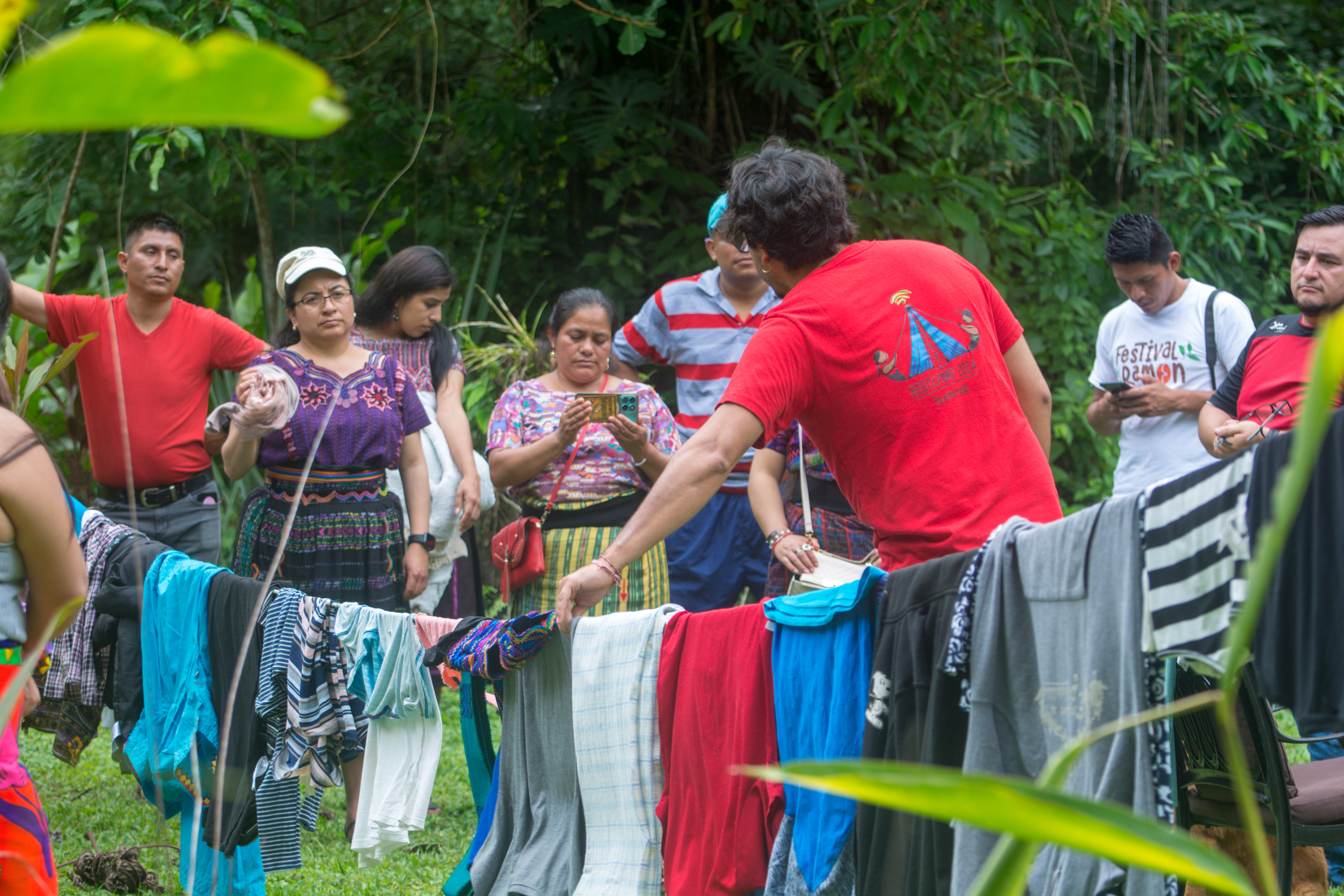 un grupo de persoans detras de una sga con numerosas prendas de vestir colgando de ella