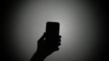 Silhouette of a hand holding a mobile phone