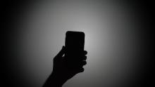 Silhouette of a person holding a smartphone