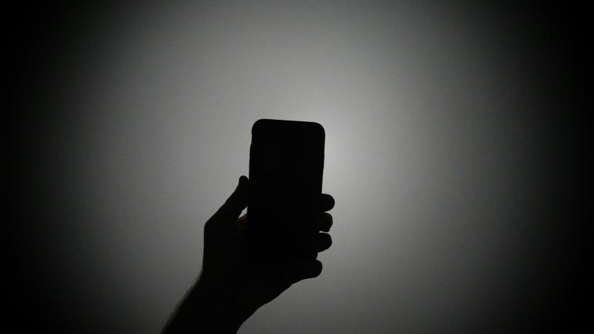 Silhouette of a hand holding a mobile phone