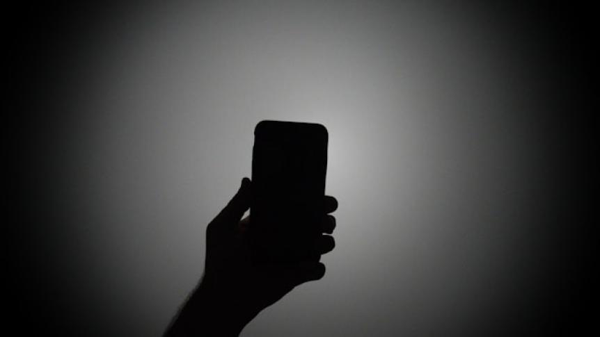 Silhouette of a person holding a smartphone